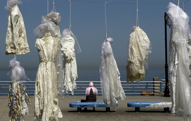 a veiled woman sits on a bench near an installation of wedding dresses by lebanese artist mireille honein and abaad ngo at beirut 039 s corniche on april 22 2017 photo afp