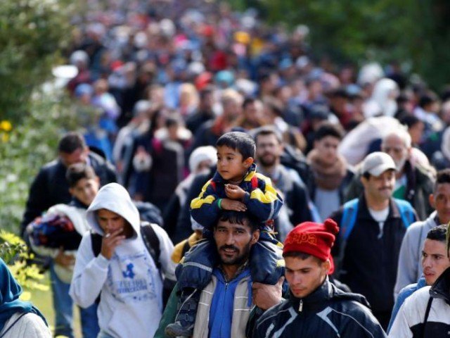 a migrant carries a child on his shoulders as they walk to cross the border with austria in hegyeshalom hungary photo reuters