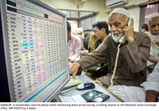 a stock broker uses his phone while monitoring share prices during a trading session at the pakistan stock exchange photo inp a stock broker uses his phone while monitoring share prices during a trading session at the pakistan stock exchange photo inp