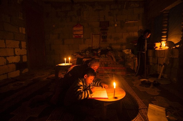 a palestinian woman helps her son study by candlelight at their makeshift home in the khan yunis refugee camp in the southern gaza strip photo afp