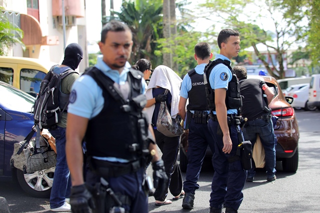 french gendarmes and police officers escort a person on april 27 2017 in saint denis de la reunion on the french indian ocean island of reunion after a man suspected of being a radicalised militant shot and wounded two policemen photo afp