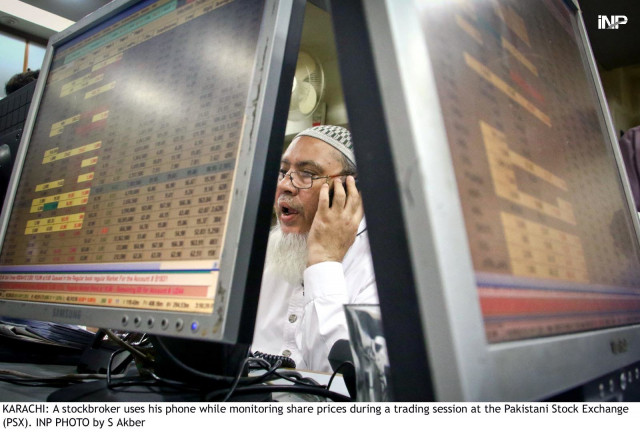 a stockbroker uses his phone while monitoring share prices during a trading session at the pakistan stock exchange photo inp a stockbroker uses his phone while monitoring share prices during a trading session at the pakistan stock exchange photo inp