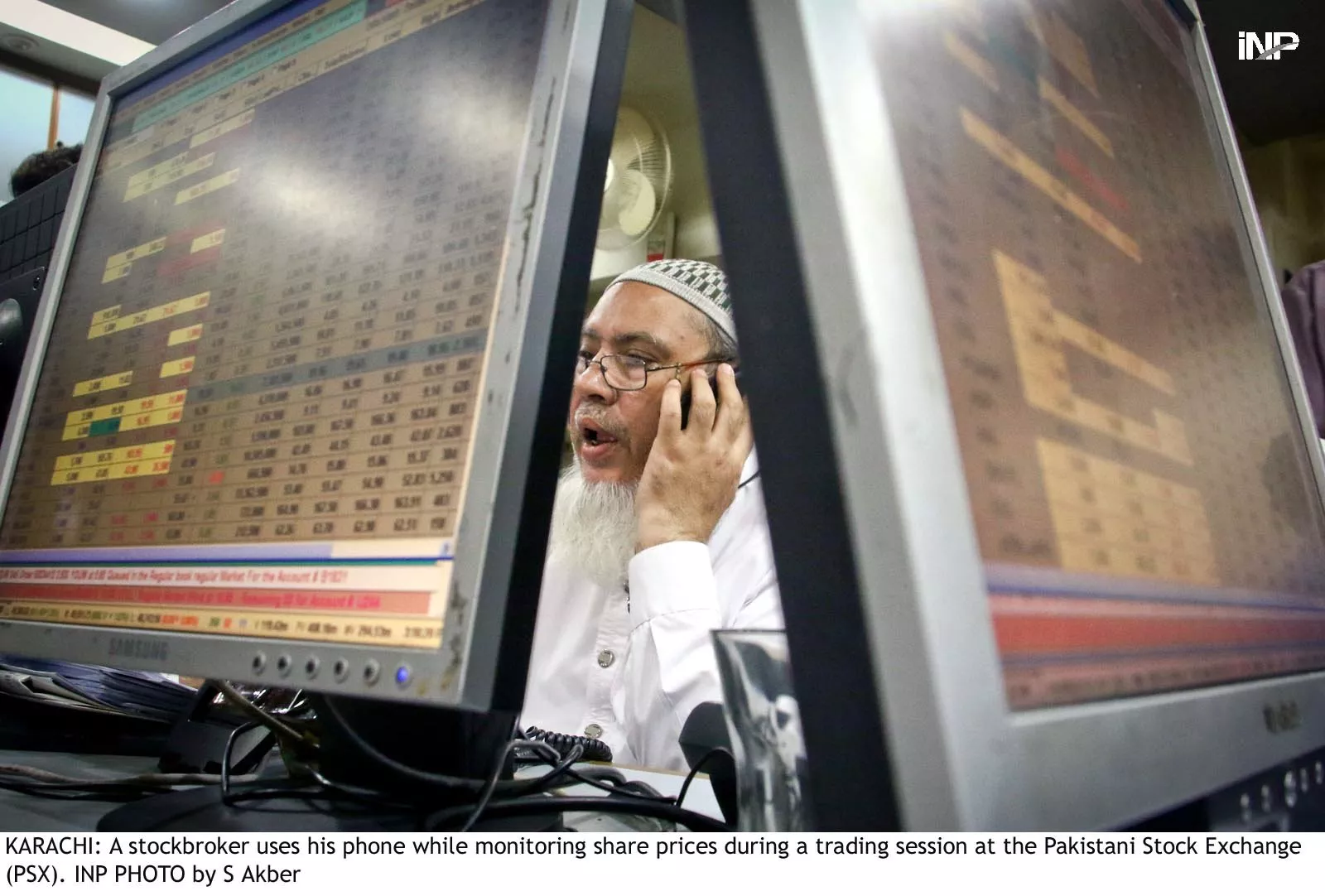 a stockbroker uses his phone while monitoring share prices during a trading session at the pakistan stock exchange photo inp a stockbroker uses his phone while monitoring share prices during a trading session at the pakistan stock exchange photo inp