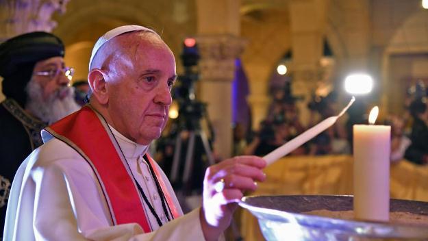 pope francis stands next to coptic pope tawadros ii as he lights a candle during a visit at the saint peter and saint paul church in cairo photo afp