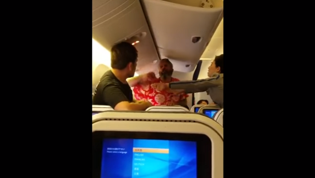 the man in the red hawaiian shirt is seen throwing punches at another male passenger screengrab