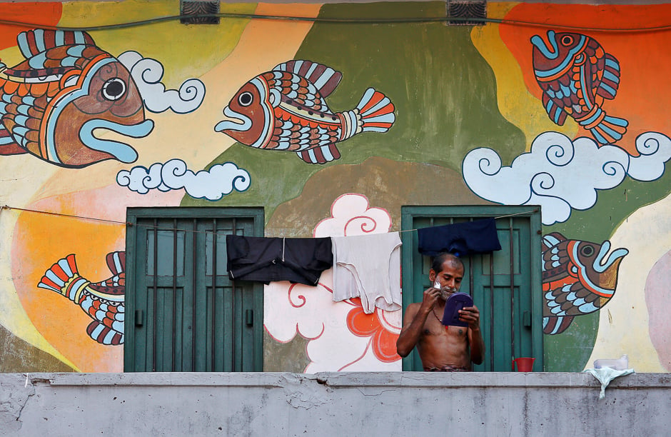 A man shaves his face on the balcony of his house at a market area in Kolkata, India. PHOTO: REUTERS