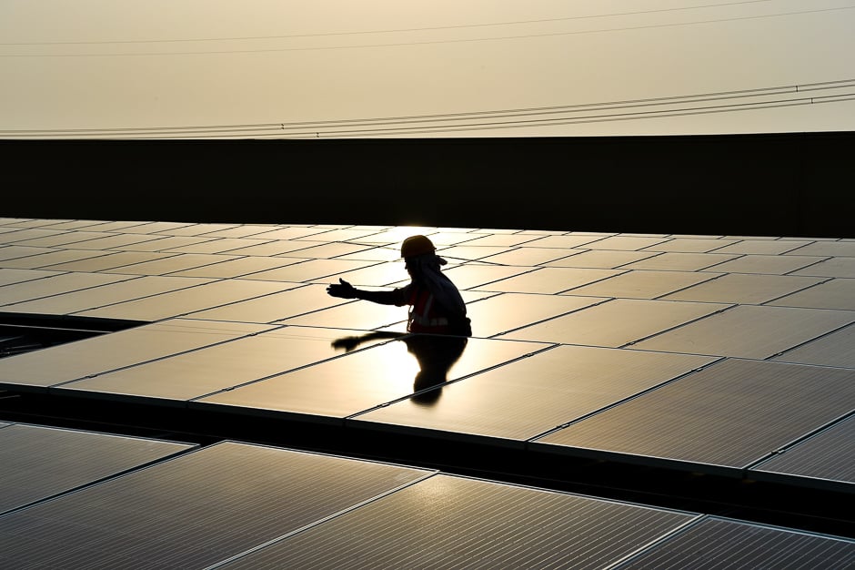 In this photograph taken on May 16, 2017, an Indian labourer installs solar panels at a site in Greater Noida, some 45km east of the capital New Delhi. PHOTO: AFP