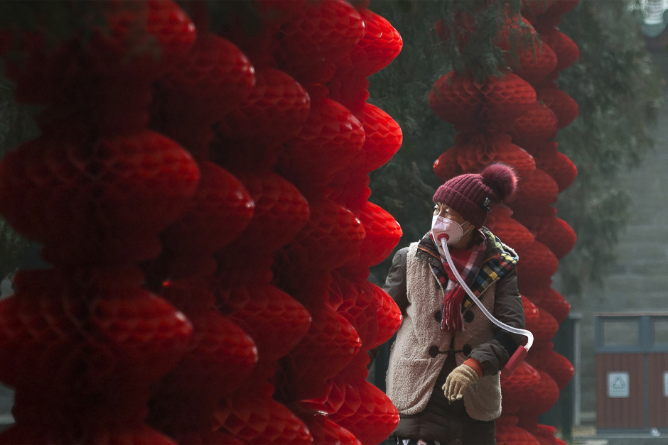 An elderly woman wearing a home-made mask walks past lanterns hung ahead of the Lunar New Year at a park in Beijing. PHOTO: AFP