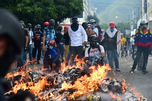 opposition demonstrators stand behind a barricade set ablaze during a protest against venezuelan president nicolas maduro in caracas on may 3 2017 photo afp