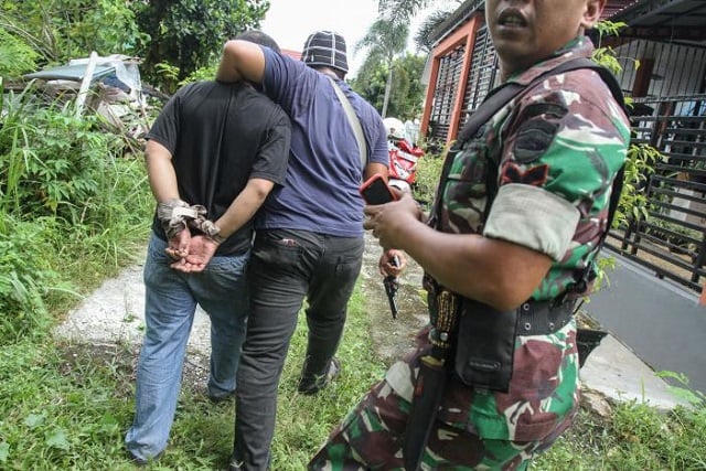 an indonesian soldier guards as a plainclothes policeman c detains a prisoner who escaped from the sialang bungkuk jail in pekanbaru on indonesia 039 s sumatra island may 5 2017 photo reuters