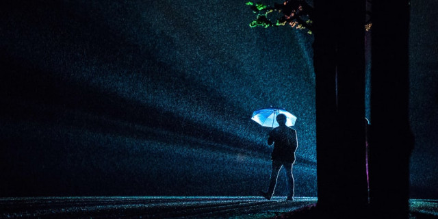 a visitor silhouettes against rays of light of the installation quot painting the night quot by austrian artist victoria coeln as rain falls on the herrenhaeuser gaerten park in hanover northern germany photo afp
