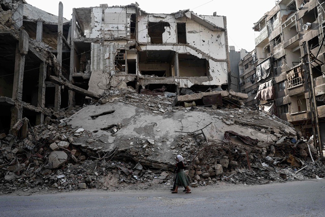 syrian girls walk past destroyed buildings in the rebel held town of douma on the eastern outskirts of damascus on may 6 2017 photo afp