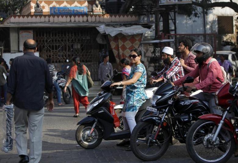 a woman riding a scooter waits for a traffic signal along a street in mumbai photo reuters