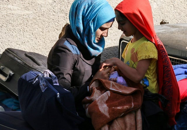 syrian families of opposition fighters gather at a staging point in the barzeh neighbourhood of the capital damascus as they wait to be evacuated photo afp