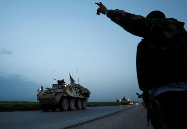 a kurdish fighter from the people 039 s protection units ypg gestures at a convoy of us military vehicles driving in the town of darbasiya next to the turkish border syria april 28 2017 photo reuters