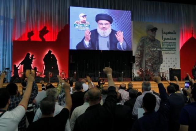 hezbollah leader sayyed hassan nasrallah addresses his supporters from a screen during a ceremony marking a year after hezbollah commander mustafa badreddine picture on banner was killed in an attack in syria in beirut 039 s southern suburbs lebanon may 11 2017 photo reuters