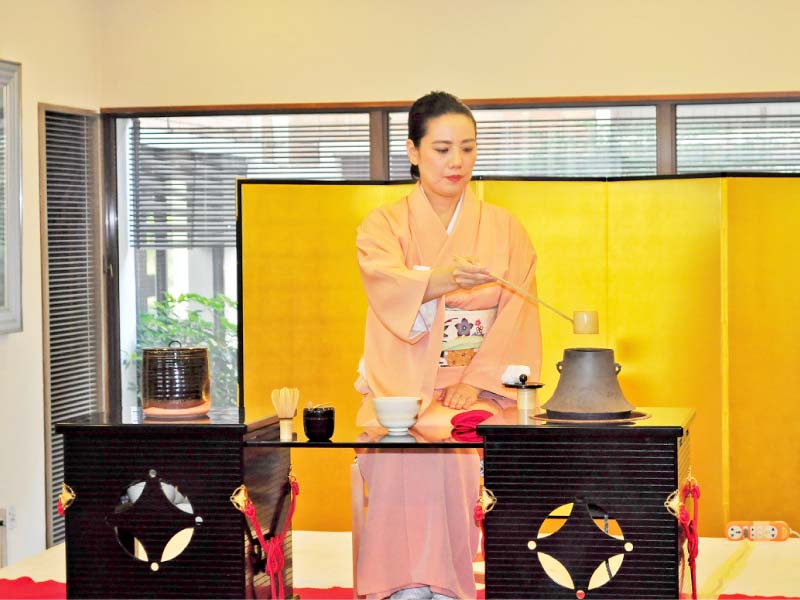 a japanese lady prepares the brew at the tea ceremony photo express