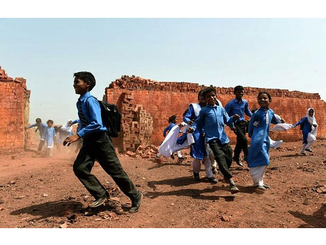 former pakistani child labourers make their way home past a brick kiln after attending classes at a school on the outskirts of lahore following a scheme that gave cash to their parents photo afp