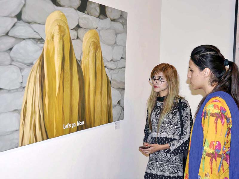 women look at a painting on display at pnca photo app