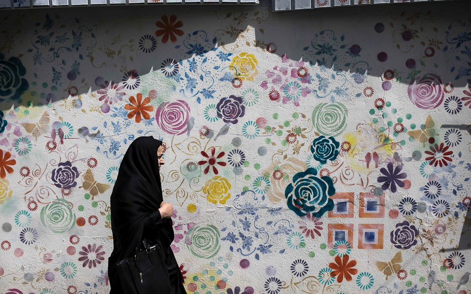 an iranian woman walks past a graffiti in tehran photo afp