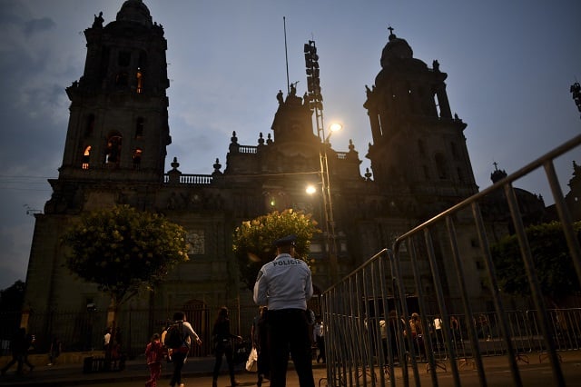 a police officer stands guard in front of the main cathedral on el zocalo square in mexico city on may 15 2017 after a knife wielding assailant stabbed a priest while delivering mass tried to flee but was caught in the church officials said photo afp