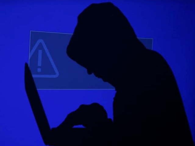 a hooded man holds a laptop computer as blue screen with an exclamation mark is projected on him in this illustration picture taken on may 13 2017 photo reuters