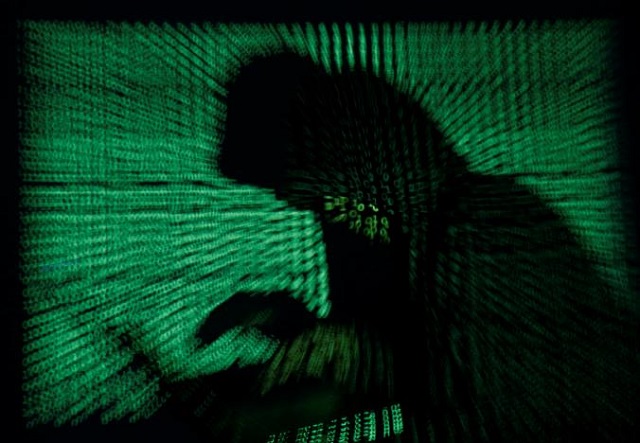 a hooded man holds a laptop computer as cyber code is projected on him in this illustration picture taken on may 13 2017 photo reuters