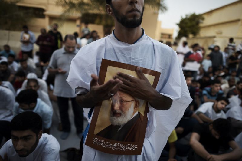 a man holds a picture of top bahraini shiite cleric sheikh isa qassim in his village of diraz near manama on june 20 2016 during a protest against the revocation of his citizenship photo afp