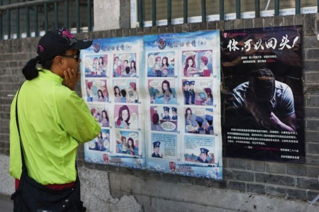 a woman looks at a propaganda cartoon warning local residents about foreign spies in an alley in beijing on may 23 2017 photo afp a woman looks at a propaganda cartoon warning local residents about foreign spies in an alley in beijing on may 23 2017 photo afp