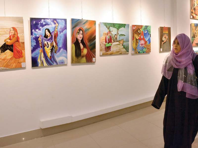 a woman walks past the paintings by karachi central jail prisoners on display at the arts council of pakistan photo jalal qureshi express