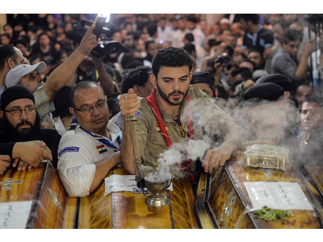 a man burns incense by a coffin as relatives of killed coptic christians gather during the funeral at abu garnous cathedral in the north minya town of maghagha on may 26 2017 photo afp