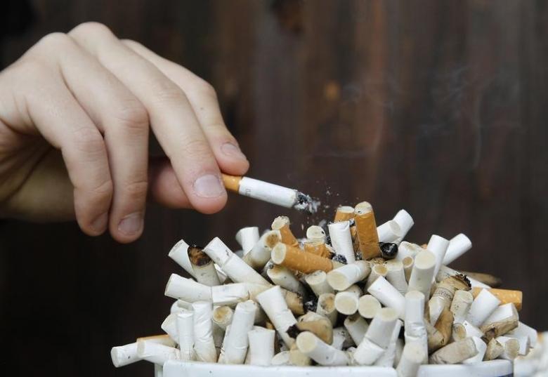 a man taps ashes off his cigarette into an ashtray filled with cigarette butts photo reuters