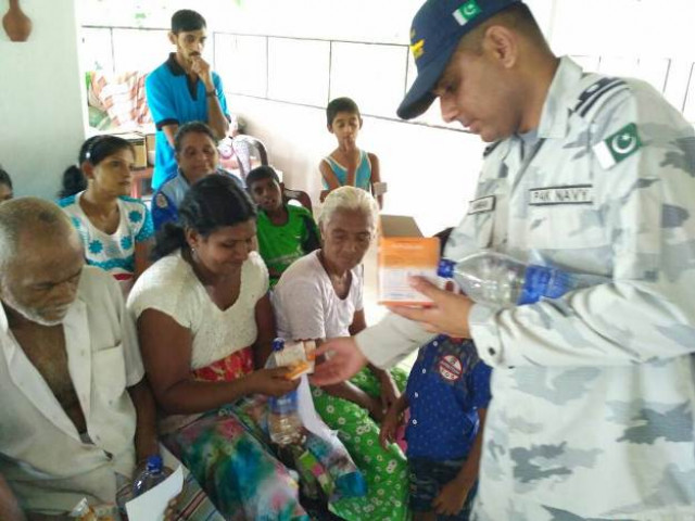 a pakistan navy officer distributes edibles among the displaced people of sri lanka 039 s flood affected areas photo pakistan navy a pakistan navy officer distributes edibles among the displaced people of sri lanka 039 s flood affected areas photo pakistan navy