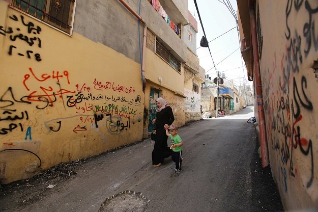palestinians walk past graffiti in dheisheh refugee camp near the west bank town of bethlehem photo afp