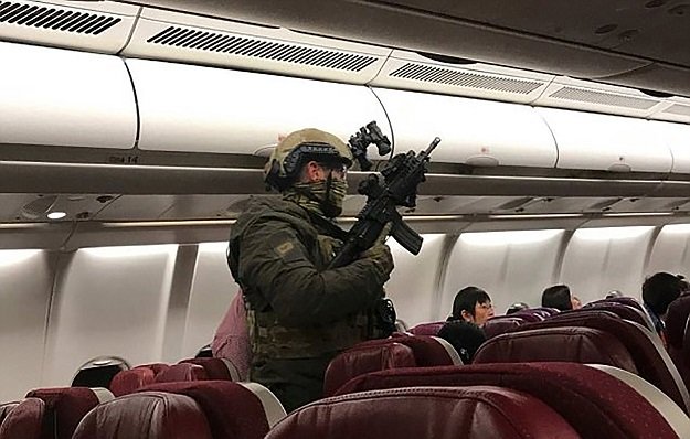 this handout photo taken and received from passenger andrew leoncelli early on june 1 2017 shows heavily armed police walking through malaysia airlines flight mh128 to arrest a sri lankan man after the flight made an emergency landing in melbourne photo afp