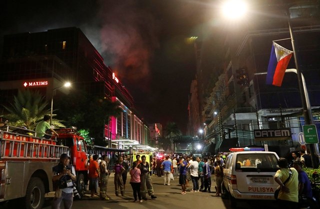 evacuated employees and guests of hotels stand along a road and watch as smoke billows from a resorts world building in pasay city metro manila philippines photo reuters