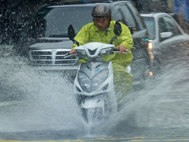 a motorcyclist rides in a flooded street in jinshan new taipei city on june 2 2017 photo afp