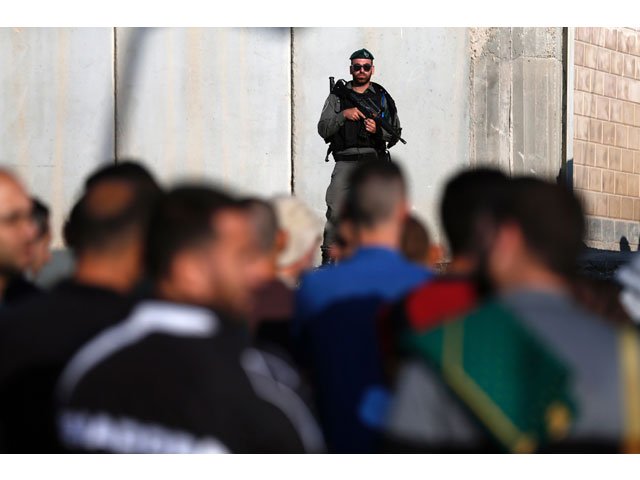 israeli security forces stand guard as palestinians wait to cross the qalandia checkpoint between the west bank city of ramallah and jerusalem as they head to jerusalem 039 s al aqsa mosque compound for the first friday prayers of ramazan on june 2 2017 photo afp