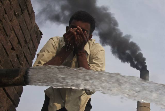 a labourer drinks water as smokes rise from a chimney of a brick factory photo reuters