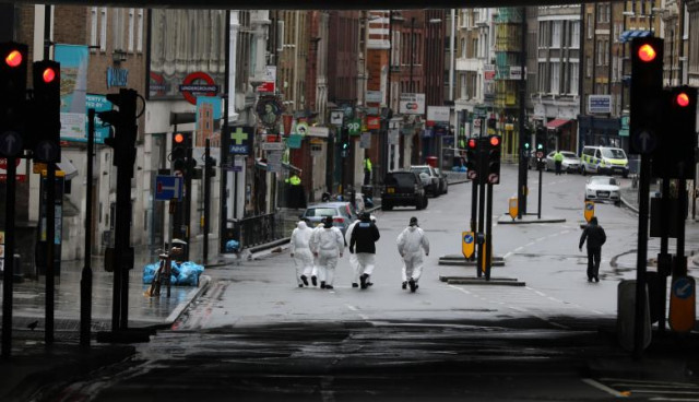 forensic officers walk along the road at the scene of the attack on london bridge and borough market london britain photo reuters