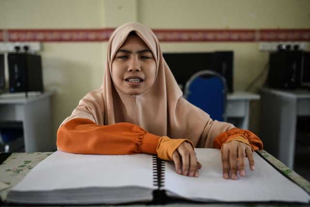 this picture taken on june 7 2017 shows a visually impaired malaysian islamic studies student reading and memorising the quran from a braille copy of the holy book at the darul quran academic institution in kuala kubu bharu photo afp