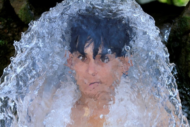 a boy holds his head against a water pipe from a canal flowing under a road bridge on the outskirts of peshawar pakistan photo reuters