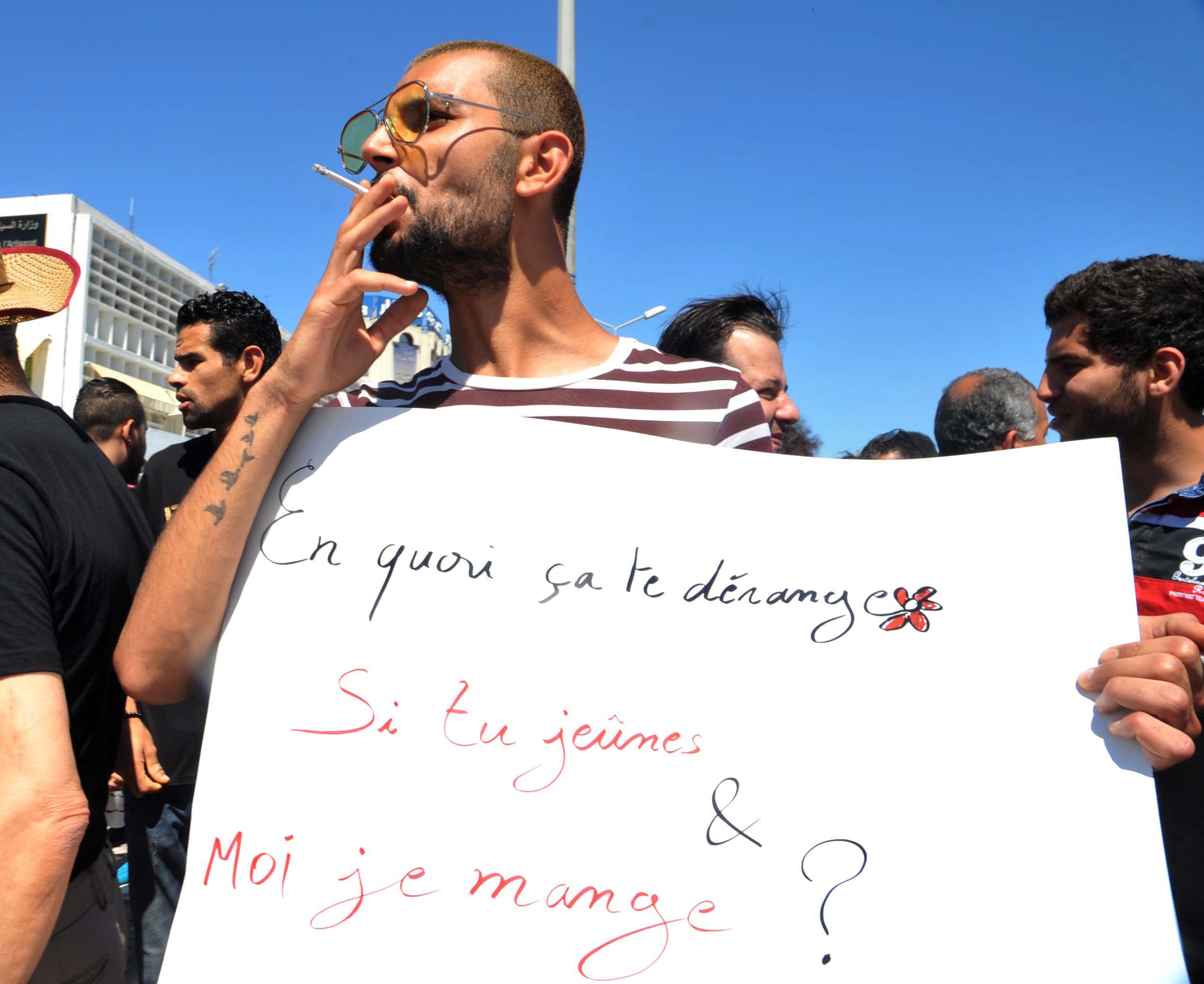 a tunisian protester smokes a cigarette and holds a placard reading in french quot why is it bothering you if you fast and i eat quot during a demonstration for the right to eat and smoke in public during the dawn to dusk fasting month of ramazan on june 11 2017 in tunis photo afp