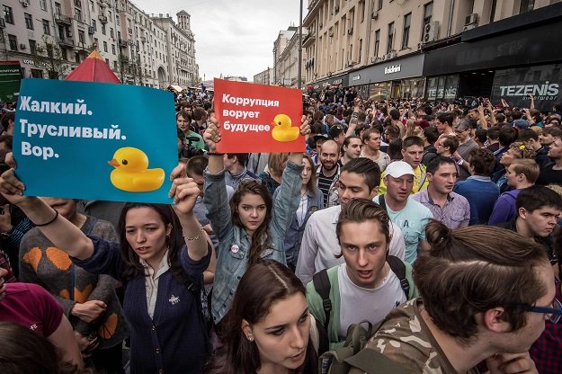 protesters hold posters reading quot corruption steals the future quot and quot miserable cowardly thief quot during an unauthorised opposition rally in central moscow photo afp