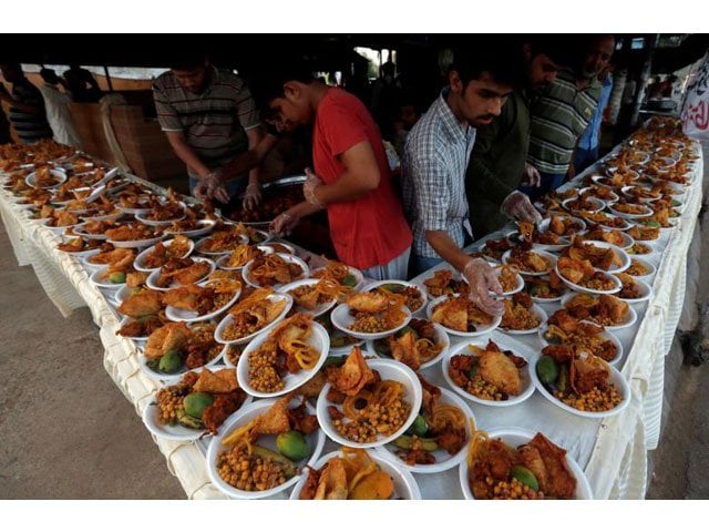 men arrange food plates for passersby to break their fast in karachi photo reuters