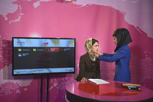 in this photograph taken on may 24 2017 an afghan woman adjusts the headscarf of a presenter l before recording at the zan tv women 039 s tv station in kabul afghan women are redrawing the media landscape in the deeply conservative country with the launch of a new magazine and a television channel risking the anger of extremists by giving their gender a glamorous voice photo afp