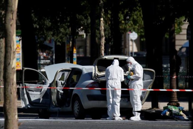 members of the scientific police inspect a burned car at the scene of an incident in which a car rammed a gendarmerie van on the champs elysees avenue in paris france june 19 2017 photo reuters