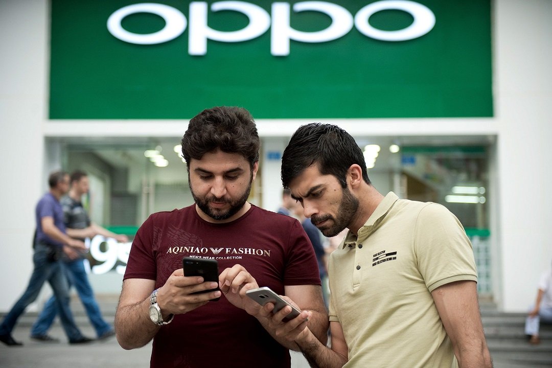 men holding smartphones stand in front of an oppo shop in shenzhen photo afp