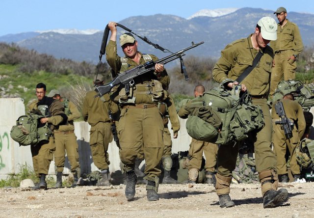 israeli soldiers carry their belongings in an area near the israel lebanon border photo reuters