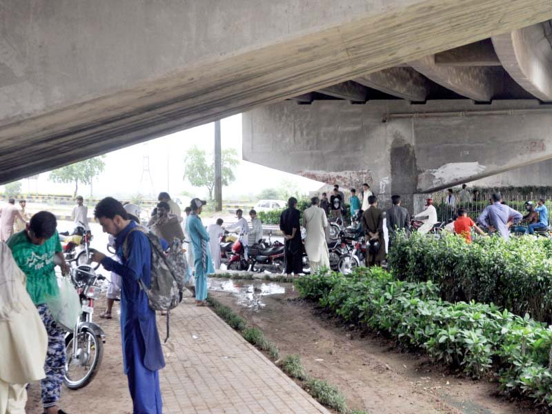 people take shelter from rain under a bridge photo zafar aslam express